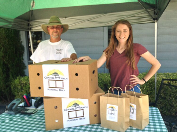 Mark and Bridget Connolly standing in front of table with boxes and bags with Connolly Ranch Natural Beef labels.