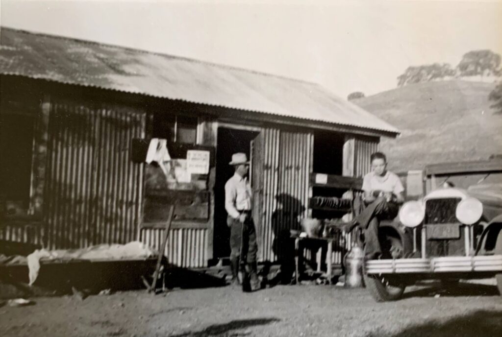 Sepia 1930s photograph of sheepherder’s cabin and vehicle with Joseph and Robert Connolly.
